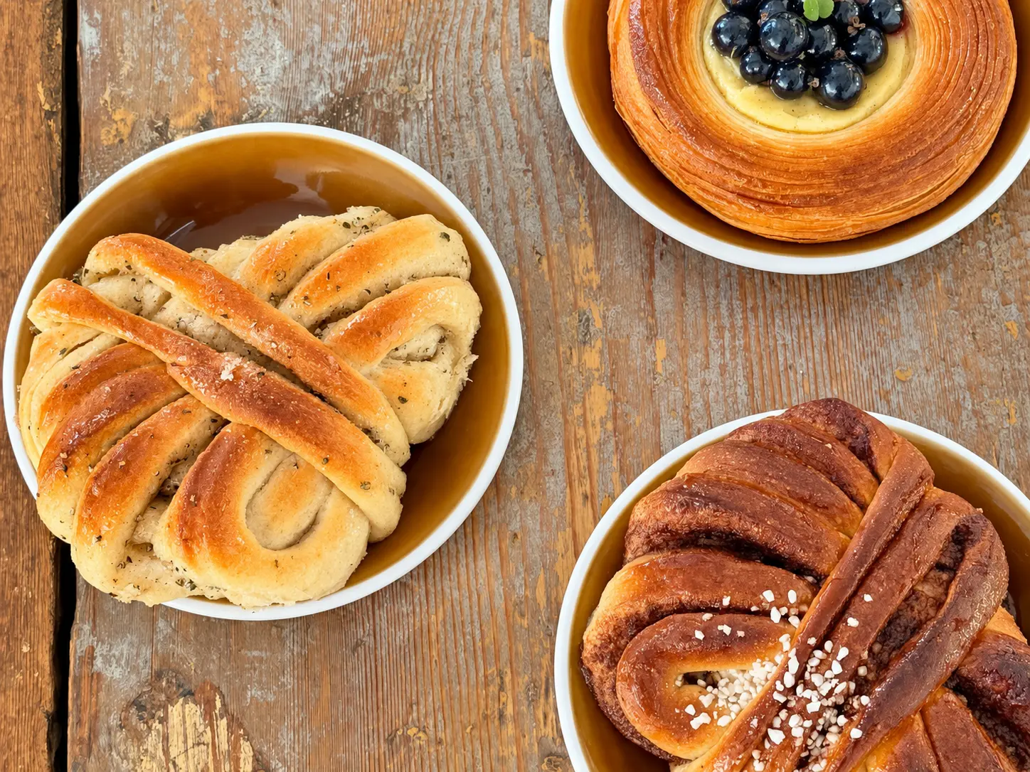 Cardamom and cinnamon buns with a berry pastry on a rustic wooden table