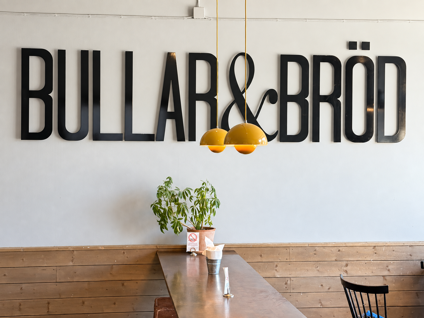 Bullar & Bröd lettering above a long wooden table and yellow pendant lamps