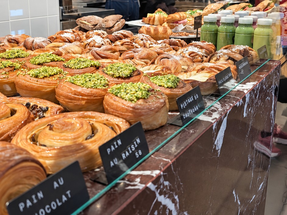 Buns and viennoiserie with pistachio topping behind Pascal's marble counter
